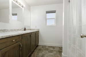 Full bathroom with vanity, a shower with curtain, and stone finish flooring
