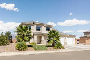 View of front of house featuring stucco siding, an attached garage, driveway, stone siding, and a front yard