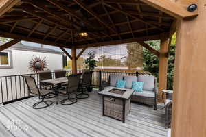 Deck featuring an outdoor fire pit, an outdoor living / dining area, a gazebo, and ceiling fan