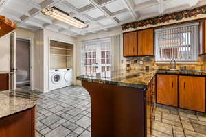 Kitchen with washer and clothes dryer, a peninsula, wood finish cabinets, decorative backsplash, and coffered ceiling