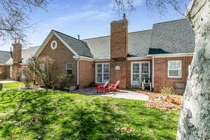 Rear view of property with a patio, brick siding, and a lawn