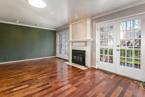Unfurnished living room with french doors, ornamental molding, dark wood-style floors, and a premium fireplace