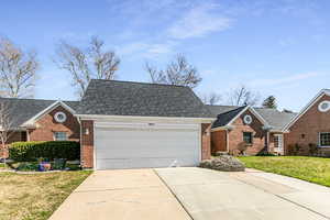 View of front of property with concrete driveway, a front lawn, brick siding, a garage, and roof with shingles