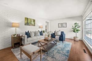 Living area featuring brick wall and wood finished floors