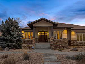 View of front of house featuring stone siding, covered porch, and roof with shingles