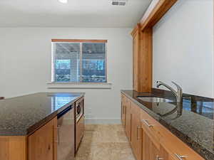 Wet bar with stainless steel appliances, dark stone counters, and light stone finish floors