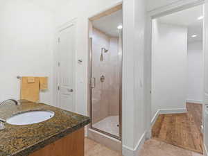 Bath featuring vanity, a stall shower, and light wood-type flooring