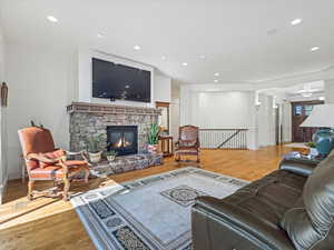 Living room with wood floors, recessed lighting, and a fireplace