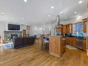 Kitchen featuring dark stone countertops, glass insert cabinets, a center island, island range hood, and open floor plan