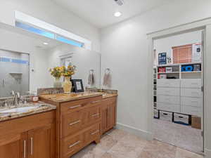 Bathroom featuring double vanity, a spacious closet, a shower stall, and recessed lighting