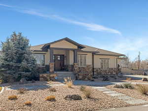 View of front of home featuring a porch, a shingled roof, and stone siding