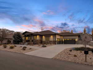 Prairie-style home featuring stone siding, an attached garage, and driveway