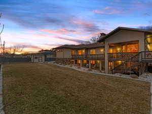 Back of house at dusk with a storage unit, a patio, a chimney, and a wooden deck