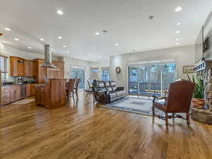 Great room with light wood floors, recessed lighting, and a stone fireplace