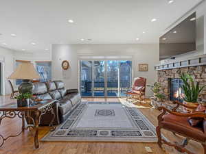 Living area with light wood floors, recessed lighting, and a stone fireplace
