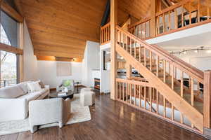 Living room with rail lighting, hardwood / wood-style floors, a vaulted wood ceiling, and a glass covered fireplace
