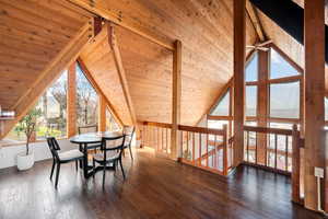 Dining space featuring plenty of natural light, dark wood-style flooring, and a high wooden beamed ceiling