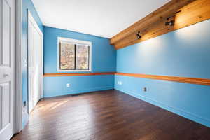 Unfurnished bedroom with dark wood-style floors, a closet, and rail lighting