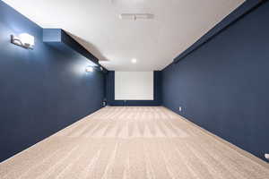 Cinema featuring a textured ceiling and light colored carpet