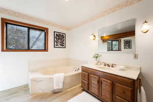 Full bathroom with vanity, a bath, and light wood-style floors