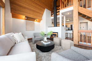 Living room with a vaulted wood ceiling, wood finished floors, and a glass covered fireplace
