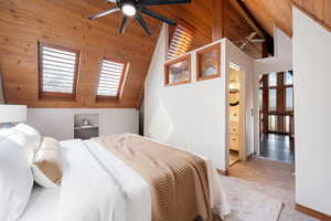 Bedroom with a high wood beamed ceiling, carpet floors, ceiling fan, and connected bathroom