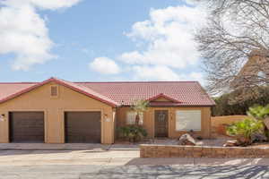 View of front of property with a tiled roof, stucco siding, an attached garage, and driveway