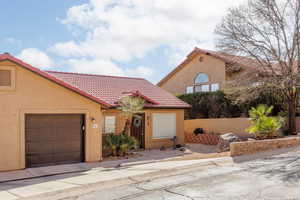 Mediterranean / spanish home with stucco siding, an attached garage, and a tile roof