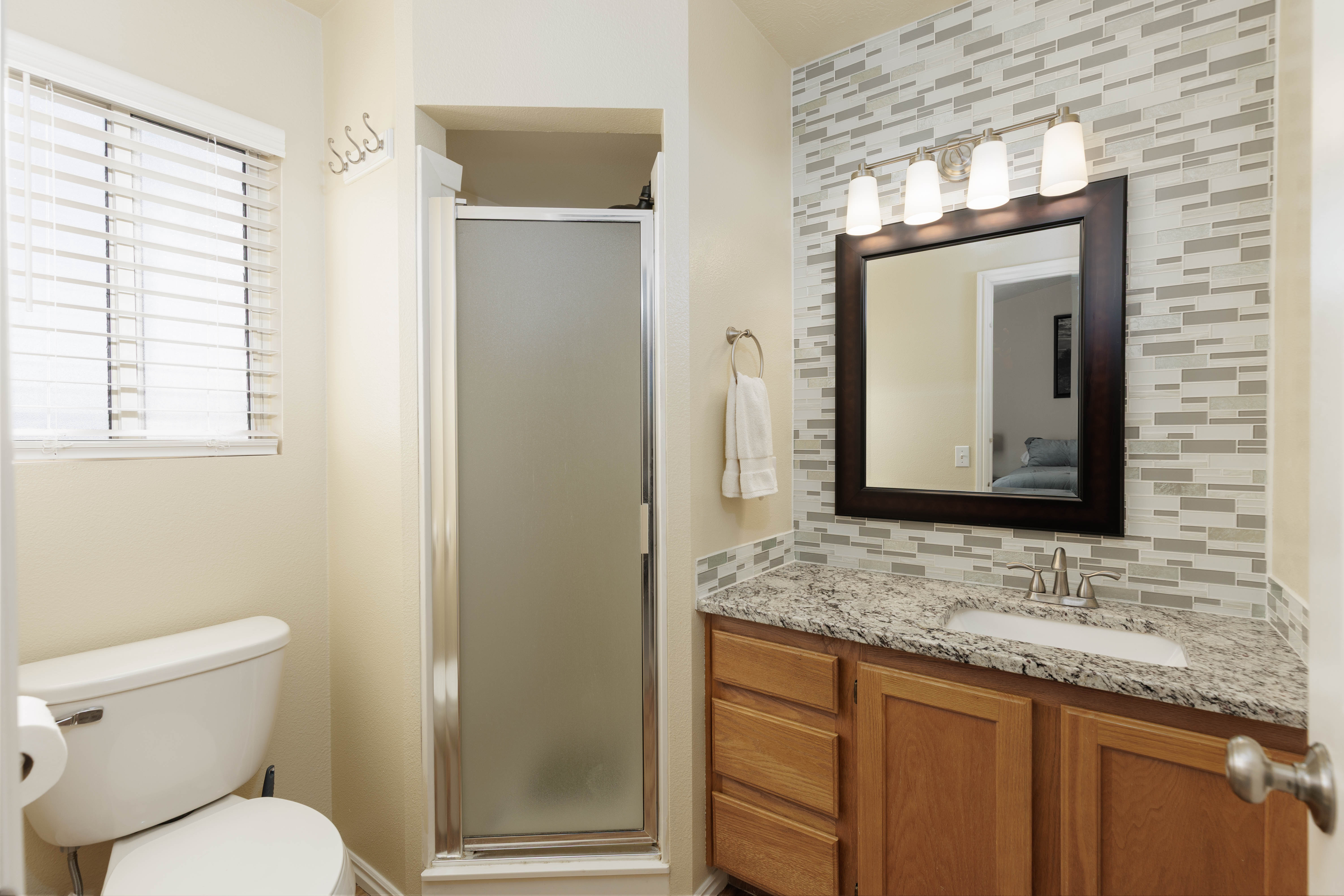 Full bath with vanity, a stall shower, backsplash, and ensuite bathroom