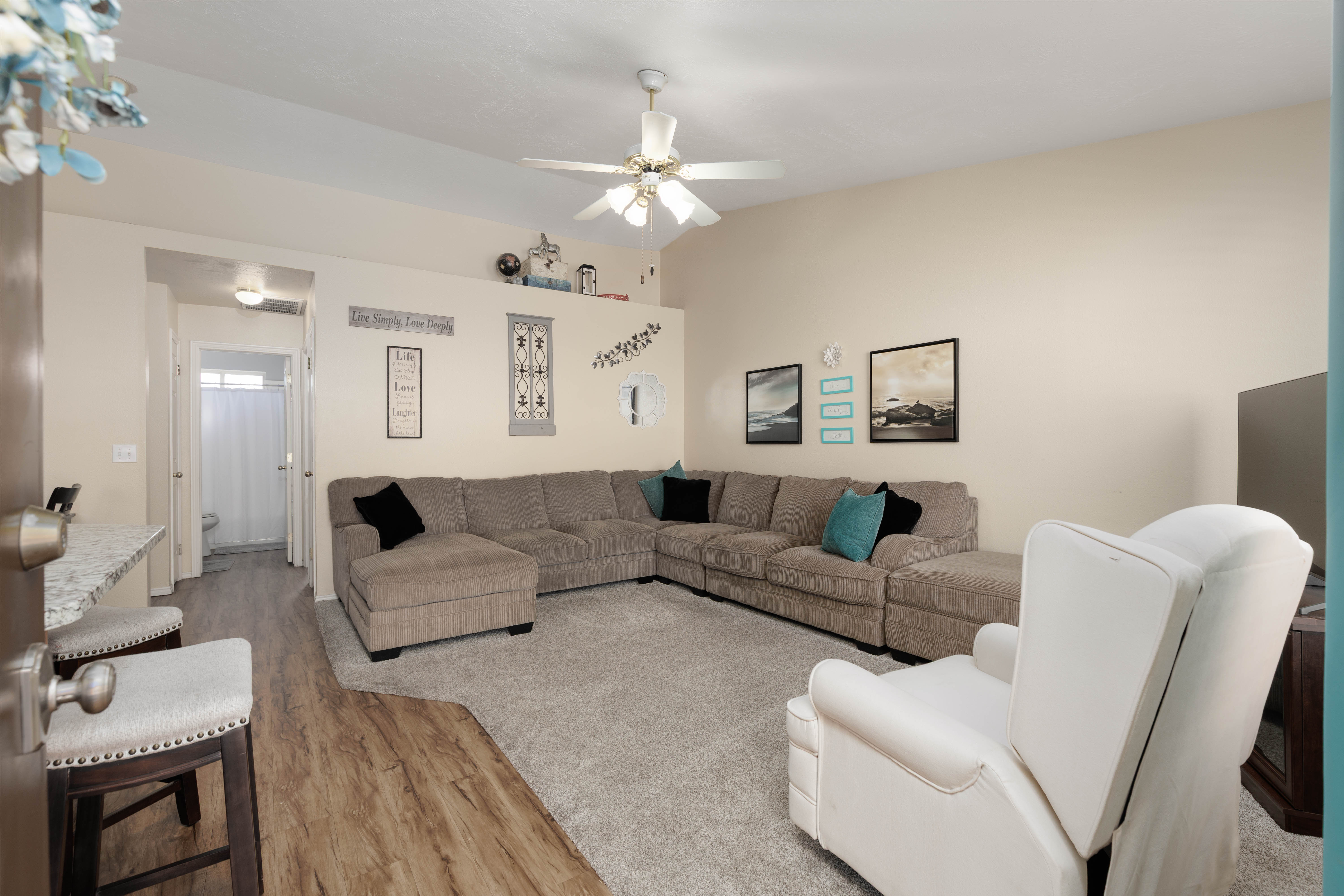 Living area with light wood finished floors, ceiling fan, and vaulted ceiling