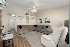 Living area with light wood finished floors, ceiling fan, and vaulted ceiling