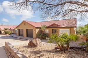 View of front of home featuring stucco siding, a tiled roof, driveway, and an attached garage