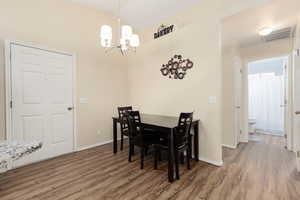 Dining space featuring lofted ceiling, wood finished floors, and suspended lighting