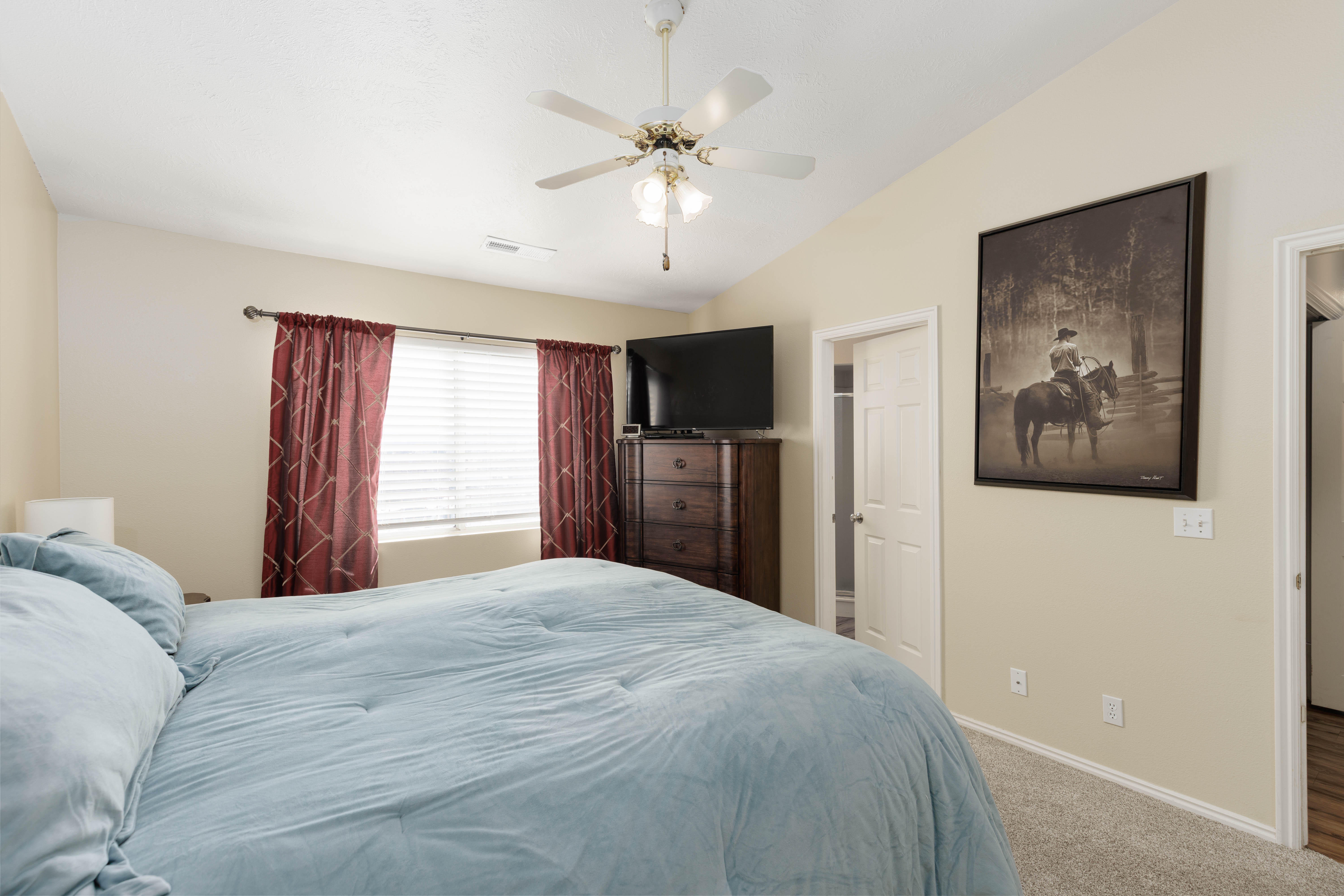Bedroom featuring lofted ceiling, carpet, ceiling fan, and connected bathroom