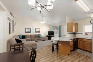 Kitchen with lofted ceiling, a peninsula, open floor plan, light wood-style flooring, and a breakfast bar area
