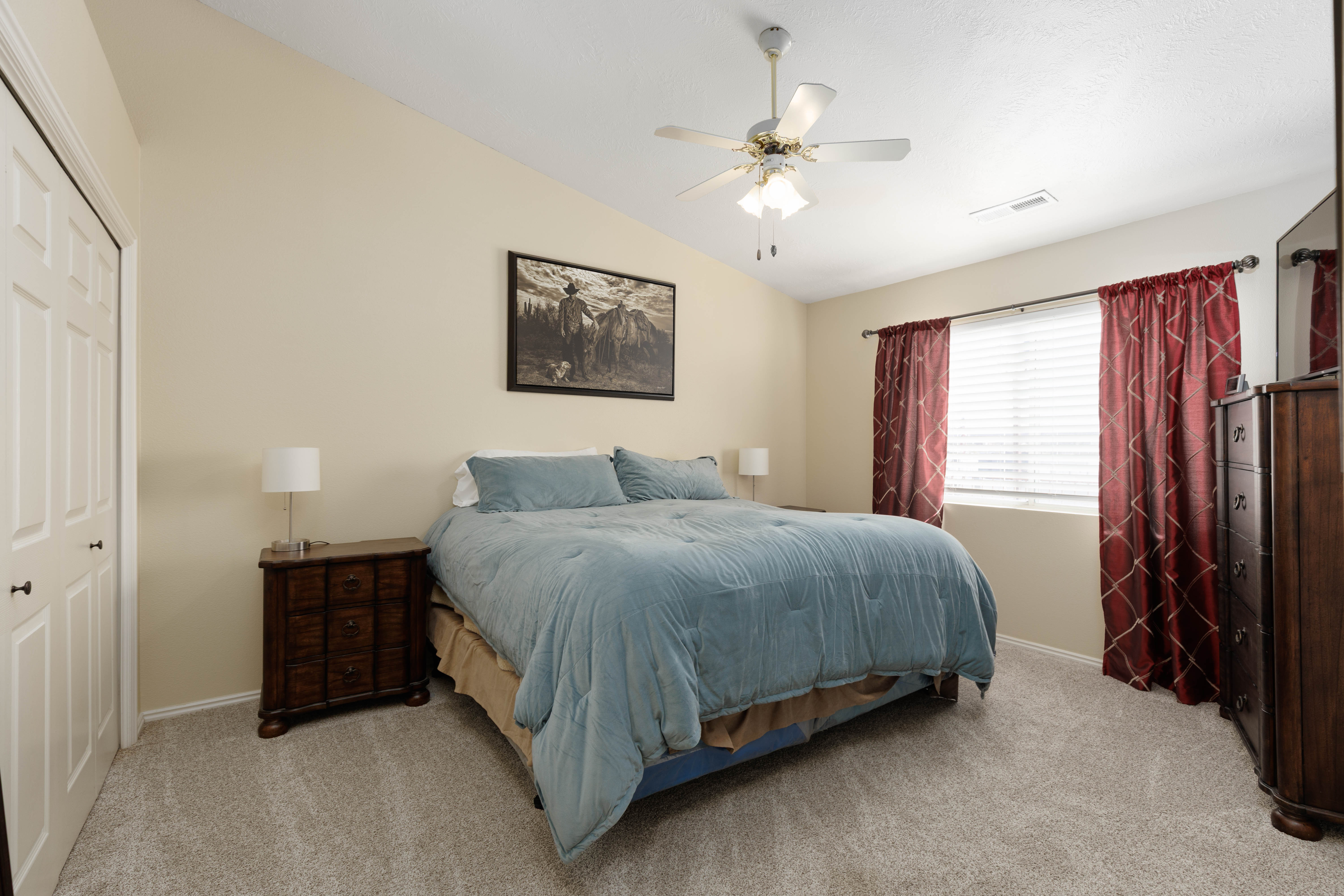Bedroom featuring vaulted ceiling, ceiling fan, light carpet, and a closet