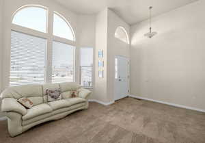 Carpeted living room with a high ceiling and plenty of natural light