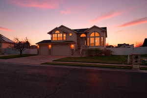 View of front facade featuring stone siding, driveway, stucco siding, and an attached garage