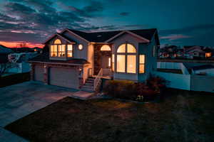 View of front of home with stone siding, driveway, stucco siding, and an attached garage