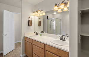 Master Bathroom with double vanity, a shower stall, and light tile patterned flooring