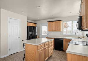 Kitchen featuring black appliances, light tile patterned floors, light countertops, a kitchen island, and recessed lighting