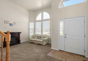 Entrance foyer featuring plenty of natural light, light carpet, a high ceiling,  and light tile patterned floors
