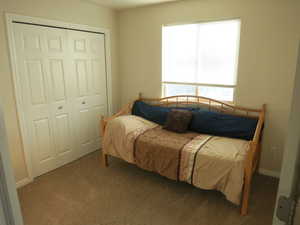 Carpeted bedroom featuring a closet and baseboards