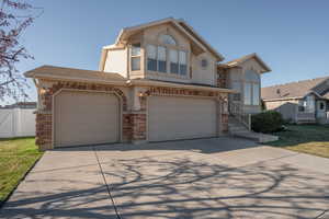 View of front of home featuring stone siding, driveway, stucco siding, and a 3 car garage