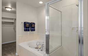 Master bathroom with a shower stall, a bath, a walk in closet, carpet, and recessed lighting