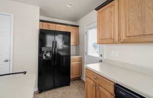 Kitchen with black appliances, light countertops, and light tile patterned floors