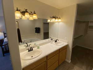 Full bathroom featuring a spacious closet, double vanity, and ensuite bath