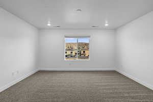 Unfurnished room featuring dark colored carpet and recessed lighting