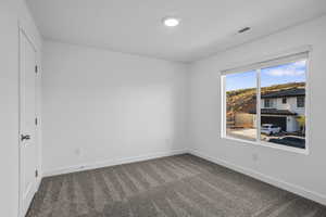 Unfurnished room with baseboards and dark colored carpet
