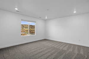 Empty room with dark carpet, recessed lighting, and a mountain view